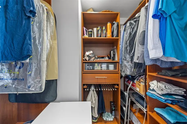 a view of walk in closet with clothes and shoes