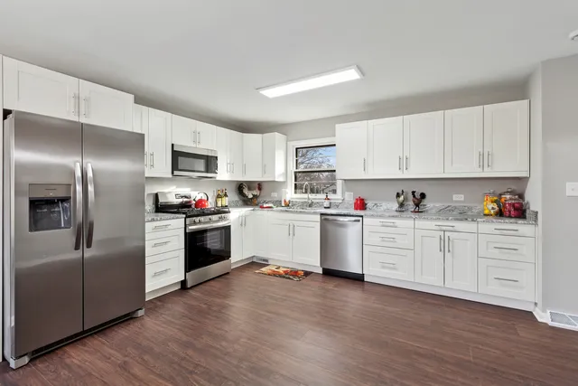 a kitchen with granite countertop white cabinets and stainless steel appliances