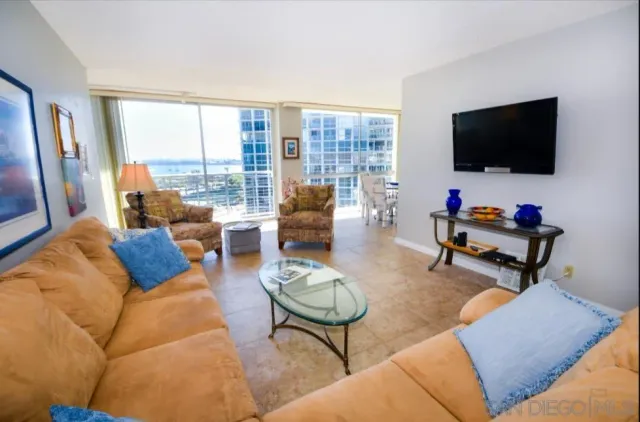a living room with furniture a flat screen tv and a floor to ceiling window
