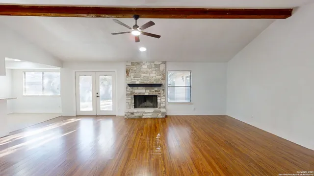 a view of an empty room with wooden floor fireplace and a window