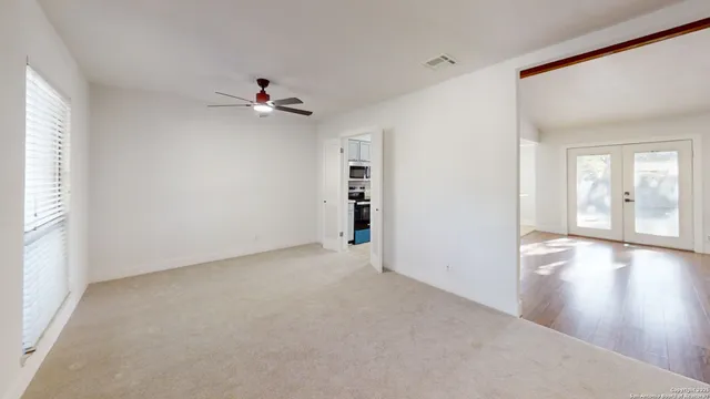 a view of empty room with wooden floor and fan