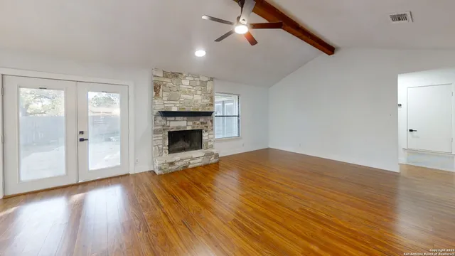 a view of empty room with wooden floor and fan