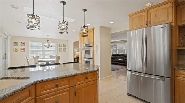 a kitchen with stainless steel appliances granite countertop a refrigerator a oven and white cabinets with wooden floors