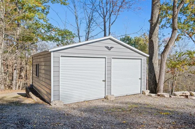 a view of a small white house with a large tree and wooden fence