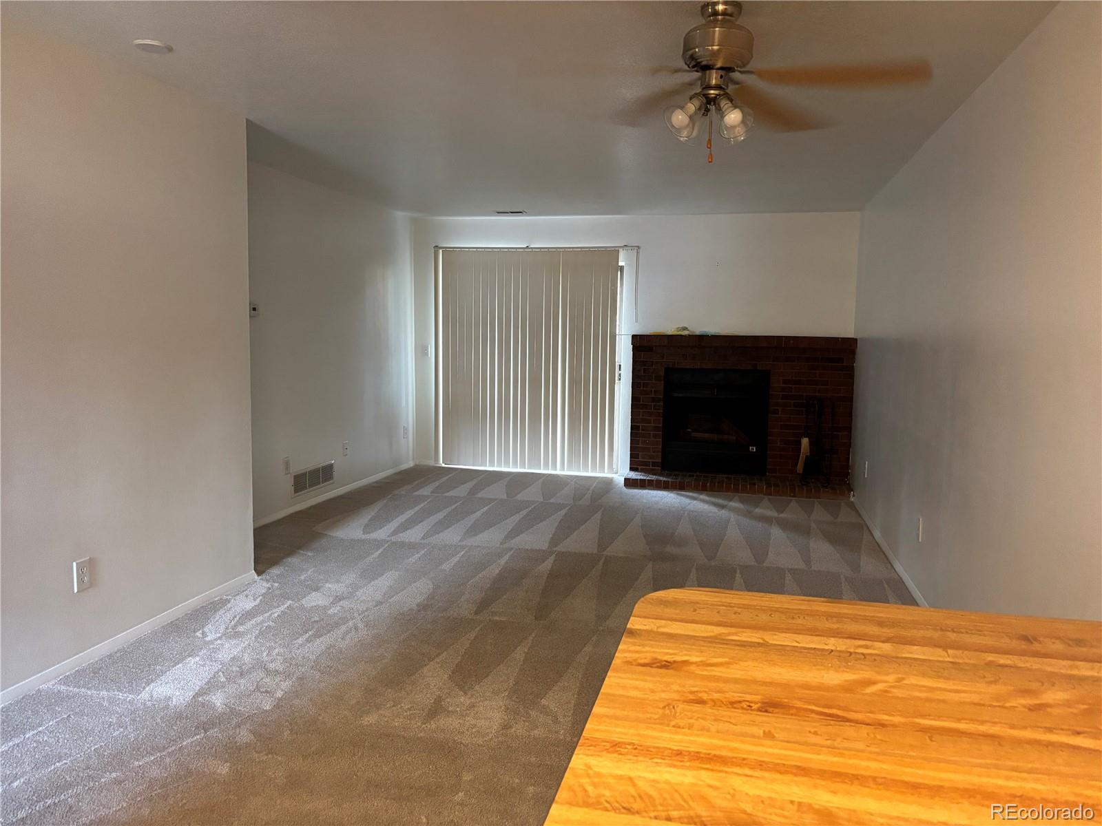 2275 South Buckley Road, Unit 101 Aurora, CO 80013 - Photo 3 of 14 an empty room with a fireplace and fan