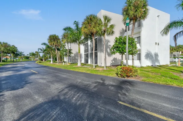 a view of a house with a big yard and palm trees