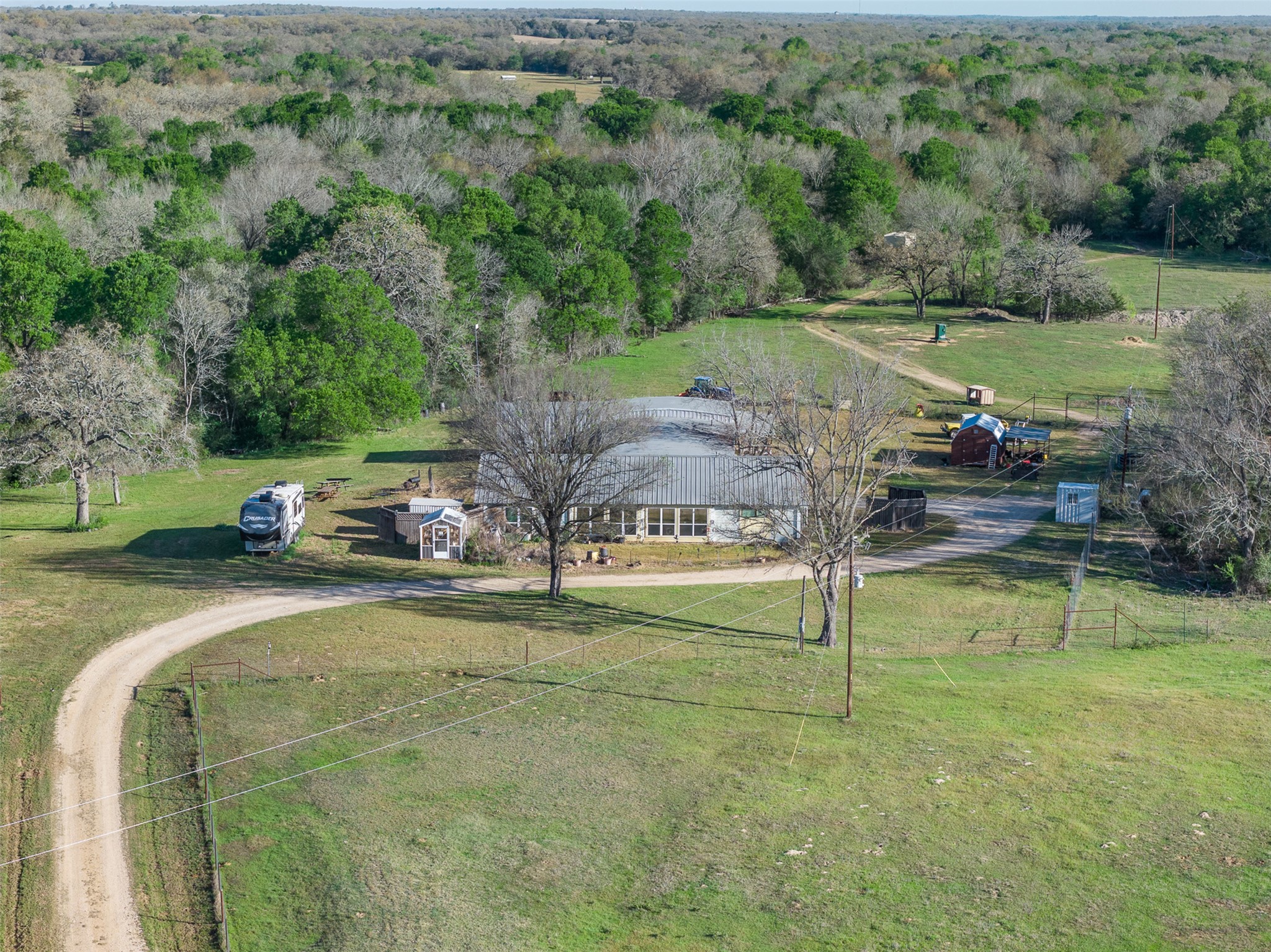 2313 Highway 79 Milano, TX 76556 - Photo 12 of 40 Expansive rural property featuring a main residence, a dirt driveway, and surrounding natural tree lines