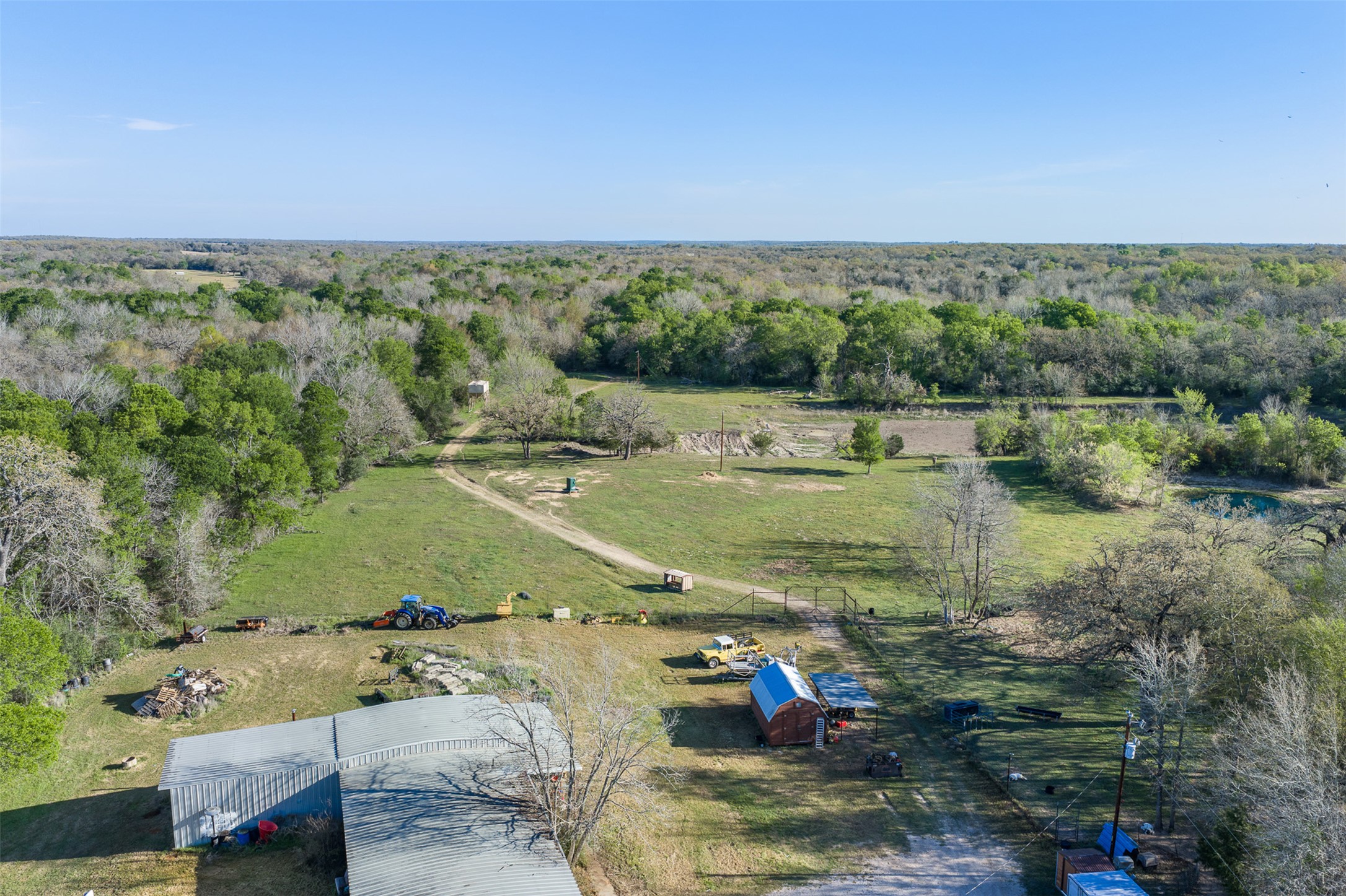 2313 Highway 79 Milano, TX 76556 - Photo 13 of 40 Expansive rural property featuring a large metal building, a smaller barn structure, and open grassy areas