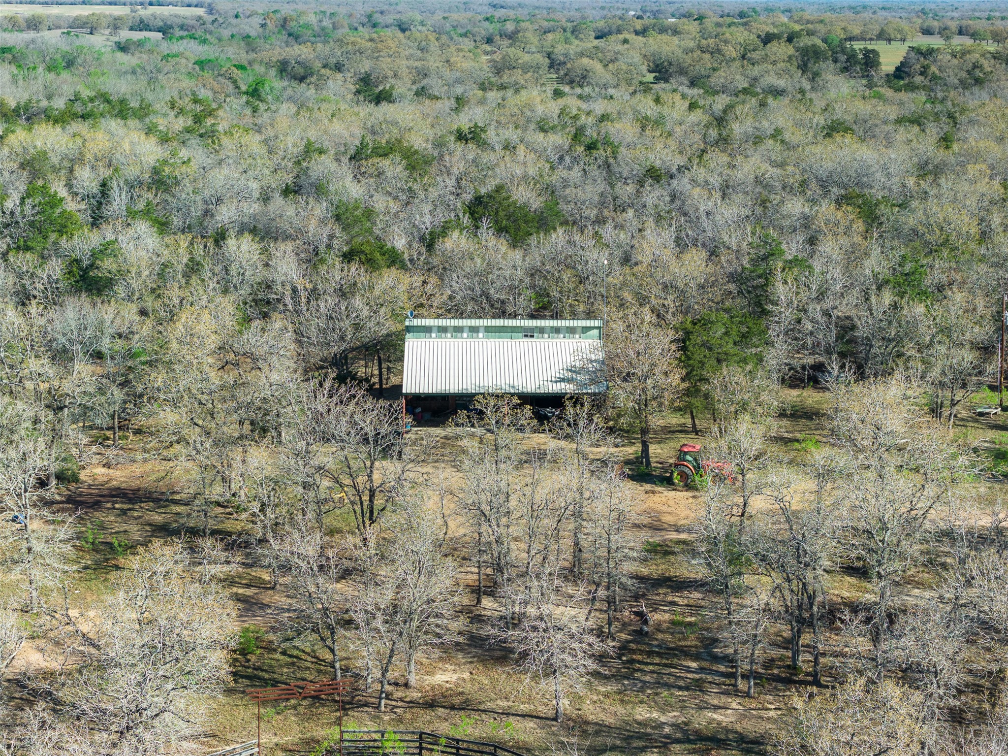 2313 Highway 79 Milano, TX 76556 - Photo 22 of 40 Sprawling acreage featuring dense tree coverage and a white metal-sided structure with a green-trimmed roof