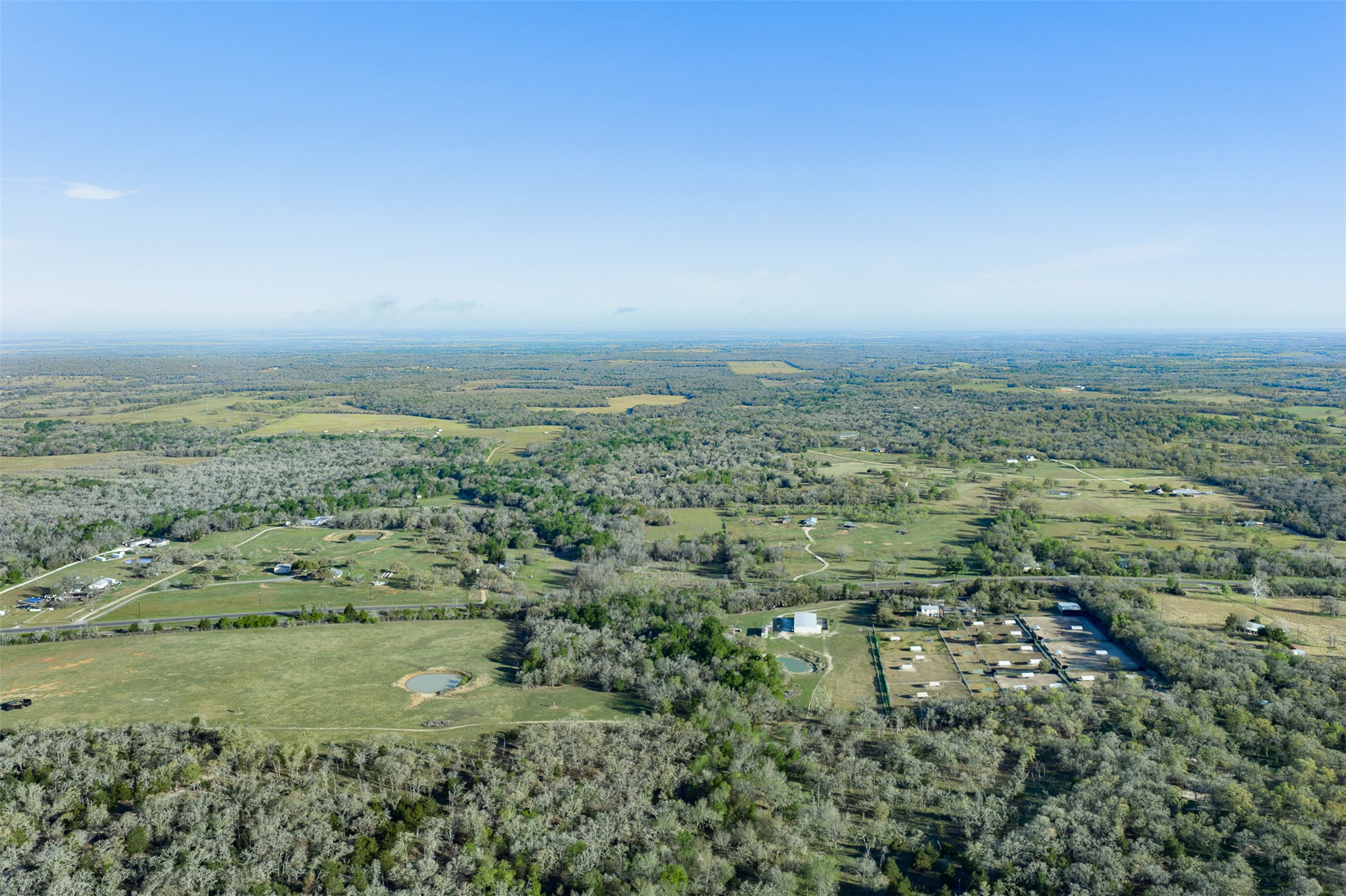 2313 Highway 79 Milano, TX 76556 - Photo 3 of 40 Expansive rural landscape featuring wooded areas, open fields, and multiple structures