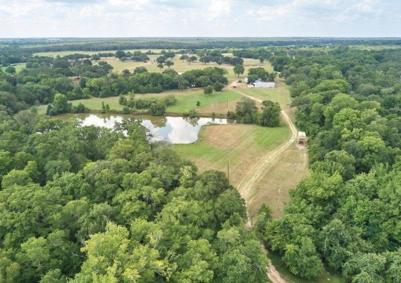 2313 Highway 79 Milano, TX 76556 - Photo 32 of 40 Expansive rural landscape featuring a private pond, open fields, mature tree lines, and a visible building structure