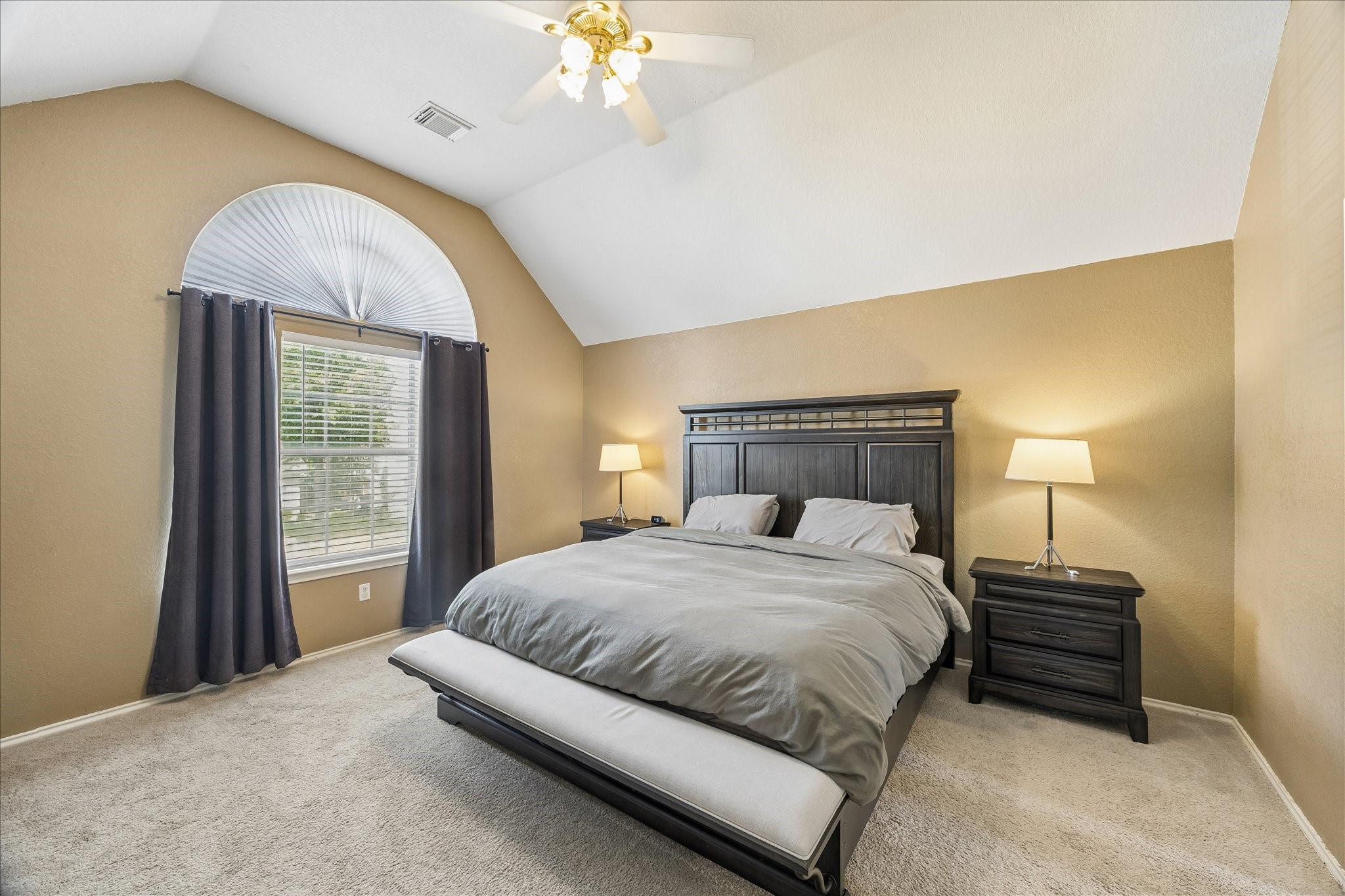 23234 Grand Rapids Lane Spring, TX 77373 - Photo 18 of 30 Spacious primary suite features a dramatic arched window, vaulted ceiling, and plush carpet — a peaceful retreat at day's end.
