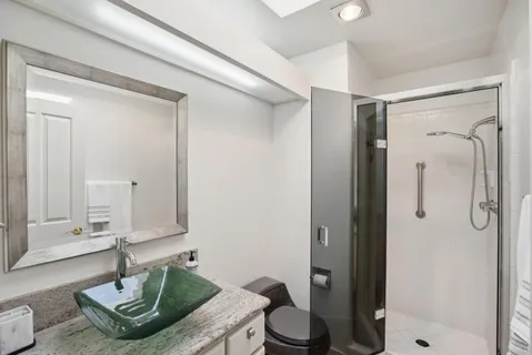a bathroom with a granite countertop sink a mirror and a shower