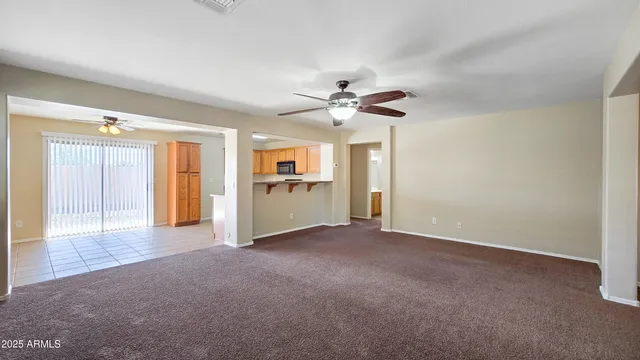 an empty room with a kitchen and a ceiling fan