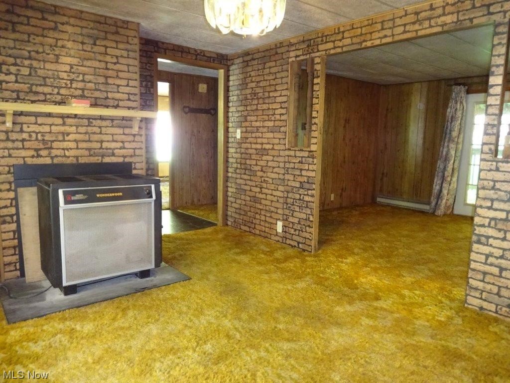 61 Milhoan Road Reedy, WV 25270 - Photo 20 of 26 Kitchen with brown cabinets, brick wall, light carpet, wooden walls, and baseboard heating