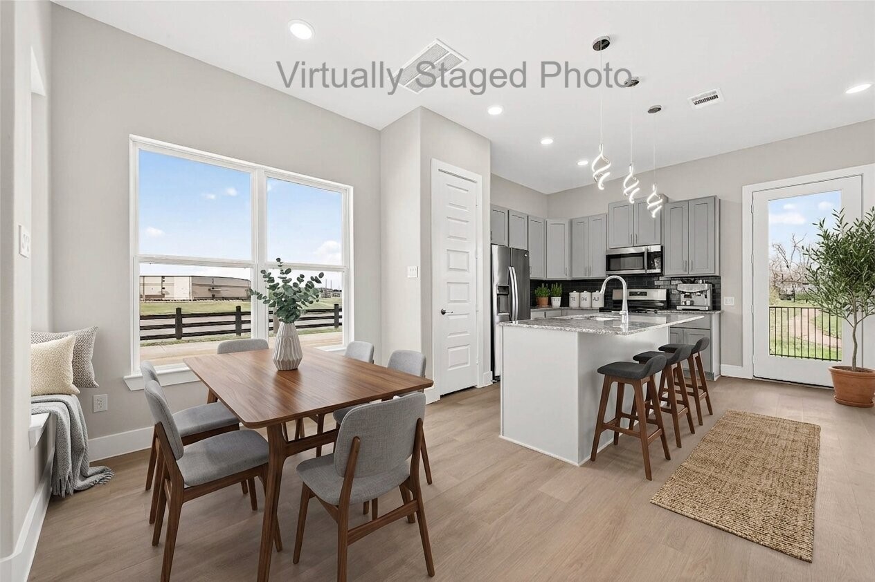 10719 Mason Road, Unit 15 Richmond, TX 77406 - Photo 4 of 50 Virtual Staging - Open-concept dining and kitchen area featuring a wooden table, a cozy window seat, and a modern island with barstool seating