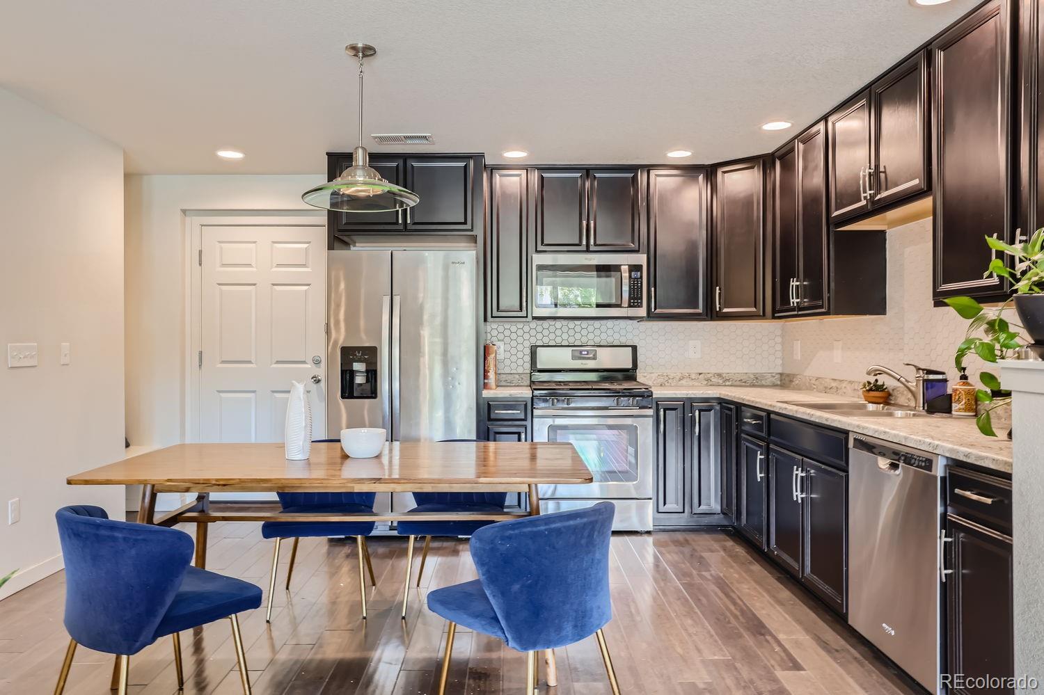 5266 Central Park Boulevard Denver, CO 80238 - Photo 11 of 23 a kitchen with a dining table chairs stainless steel appliances and cabinets