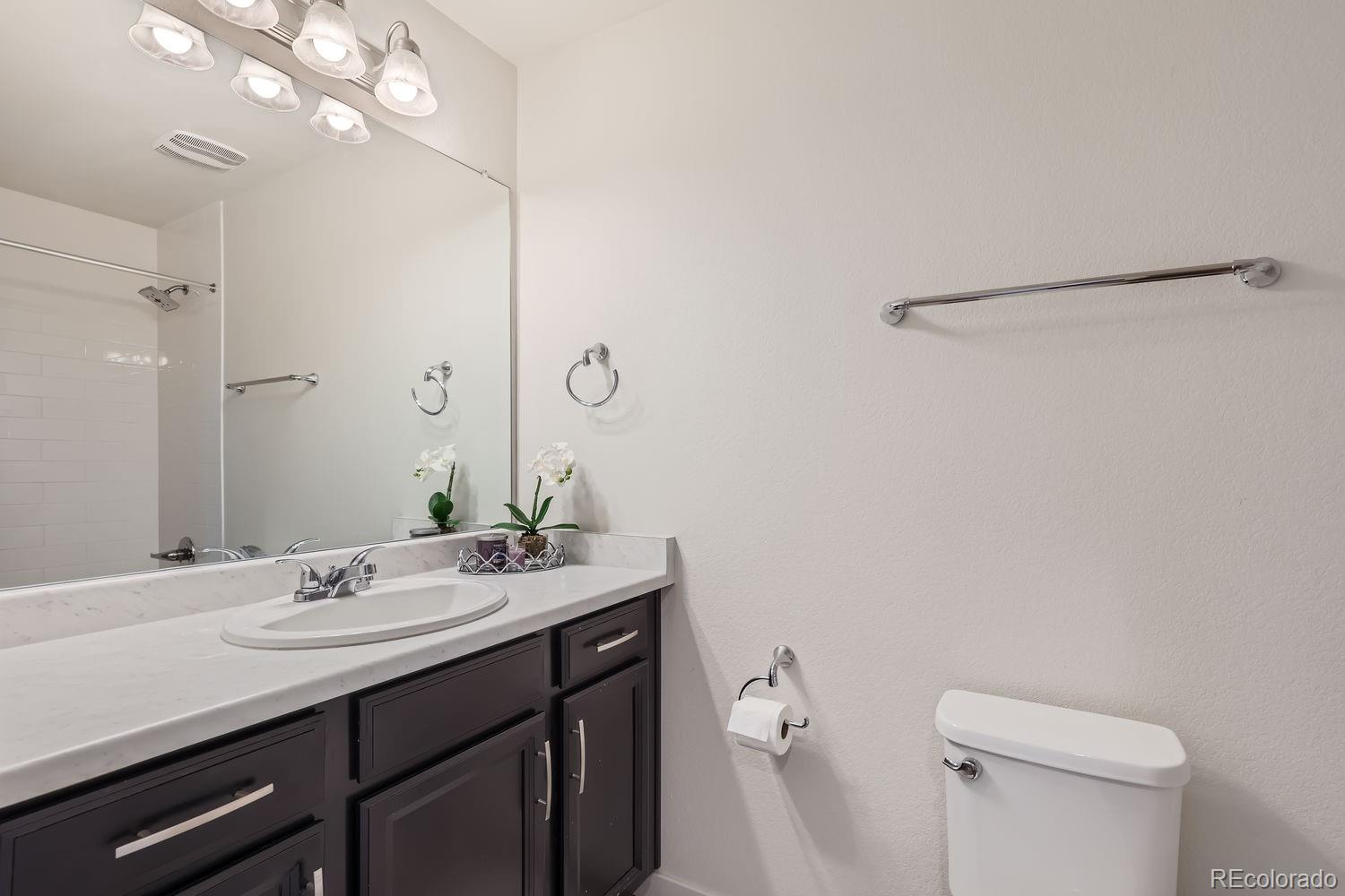 5266 Central Park Boulevard Denver, CO 80238 - Photo 19 of 23 a bathroom with a granite countertop sink a toilet and a mirror