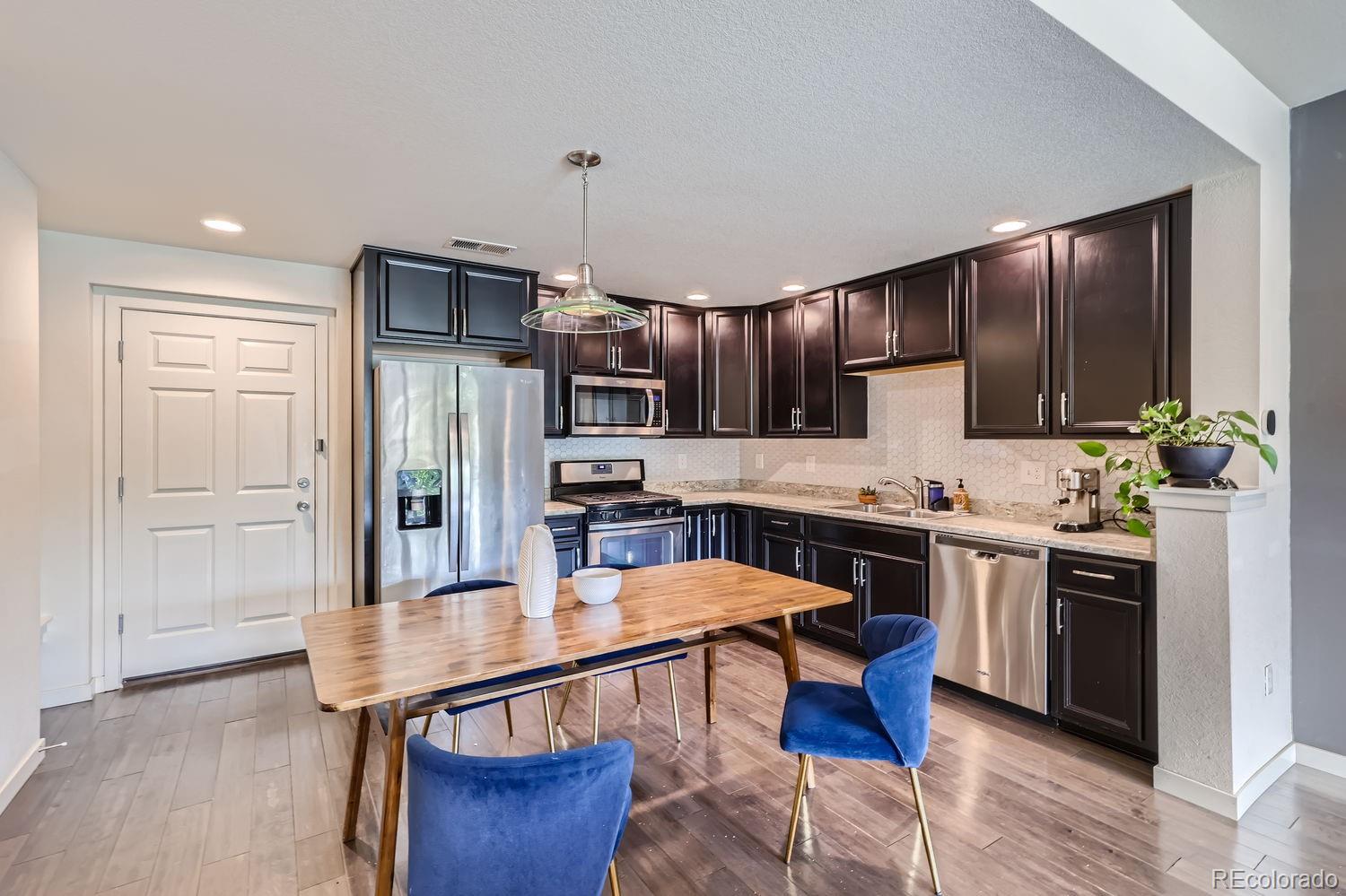 5266 Central Park Boulevard Denver, CO 80238 - Photo 9 of 23 a kitchen with stainless steel appliances kitchen island granite countertop a refrigerator a stove a sink dishwasher and white cabinets with wooden floor