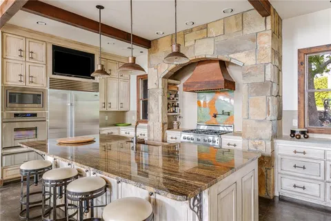 a kitchen with stainless steel appliances kitchen island granite countertop a table chairs in it and wooden floors