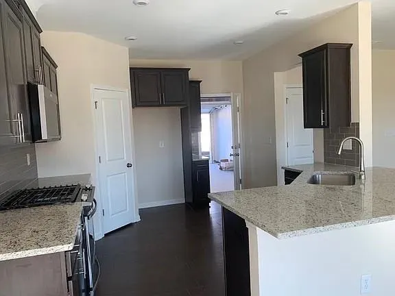 a kitchen with granite countertop a sink stove and refrigerator