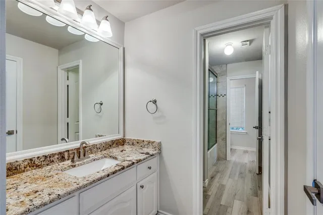 a bathroom with a granite countertop sink a mirror and a shower