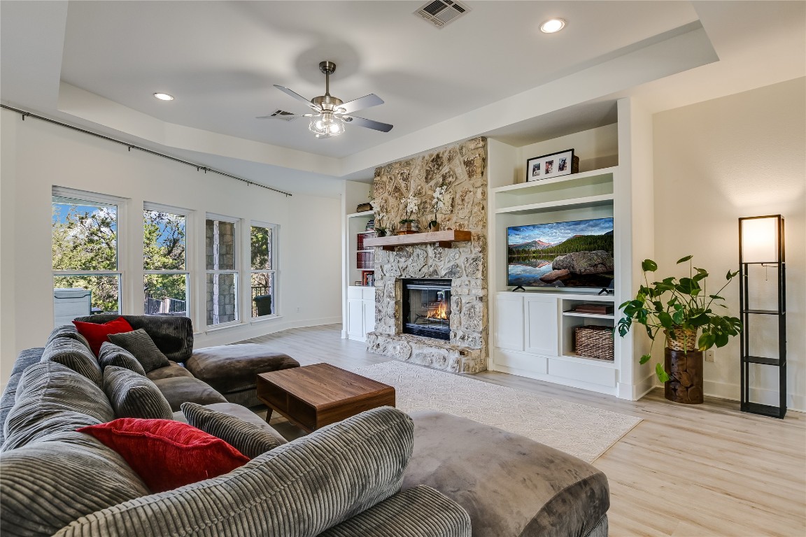 945 Wesley Ridge Drive Spicewood, TX 78669 - Photo 16 of 40 A stone fireplace and built-in shelving anchors the living space, creating a warm and welcoming atmosphere.