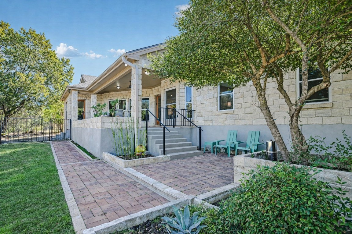 945 Wesley Ridge Drive Spicewood, TX 78669 - Photo 19 of 40 Brick walkways and patio areas surround the covered outdoor living space. (Photo has been virtually staged to reflect a spring landscape.)
