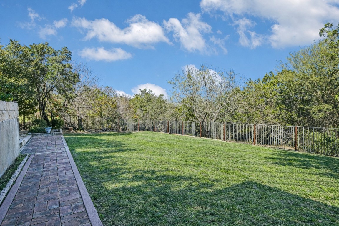 945 Wesley Ridge Drive Spicewood, TX 78669 - Photo 20 of 40 A fenced backyard showcases open lawn space. The home is situated on approximately 0.56 acres with the back lot line extending beyond the fence. (Photo has been virtually staged to reflect a spring landscape.)