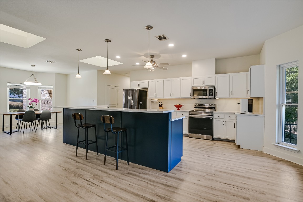 945 Wesley Ridge Drive Spicewood, TX 78669 - Photo 9 of 40 Kitchen overview featuring a large central island with bar seating, anchoring the heart of the home and connecting seamlessly to surrounding areas.