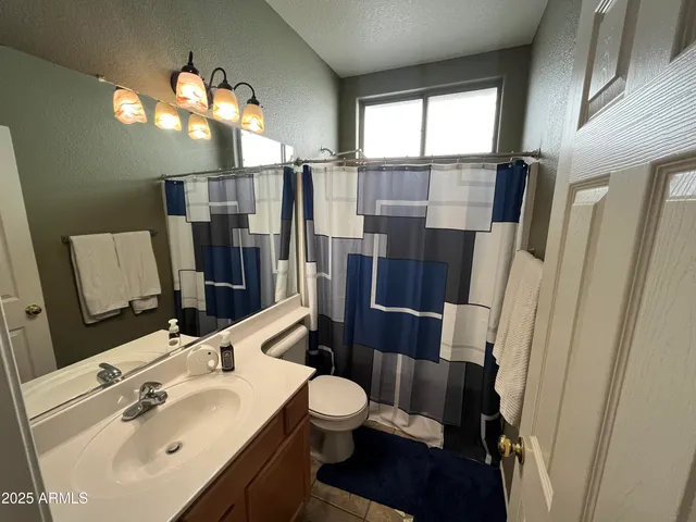 a bathroom with a sink a toilet a mirror and shower