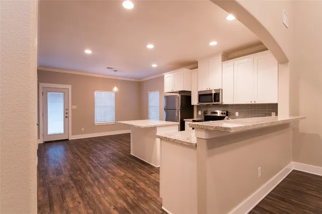 a view of kitchen with stainless steel appliances granite countertop a stove top oven a sink and a refrigerator