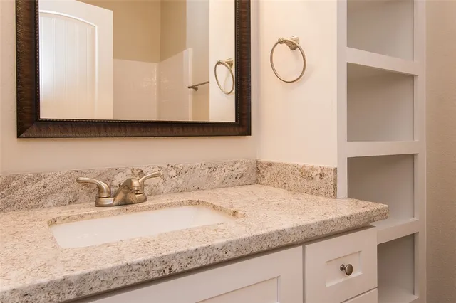 a bathroom with a granite countertop sink and a mirror