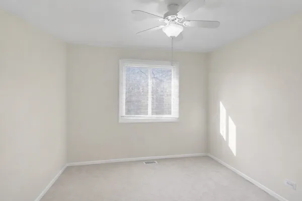 an empty room with a window and a fan