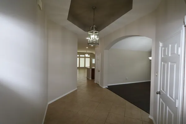 en empty room with wooden floor chandelier and windows