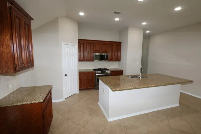 a kitchen with stainless steel appliances granite countertop a sink a stove and a refrigerator