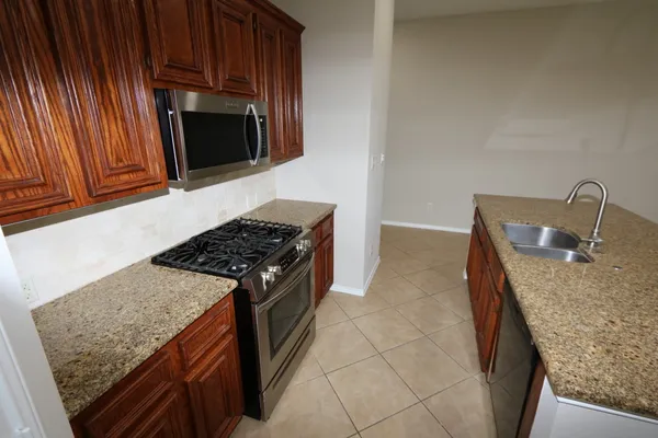 a kitchen with granite countertop a stove top oven microwave and cabinets