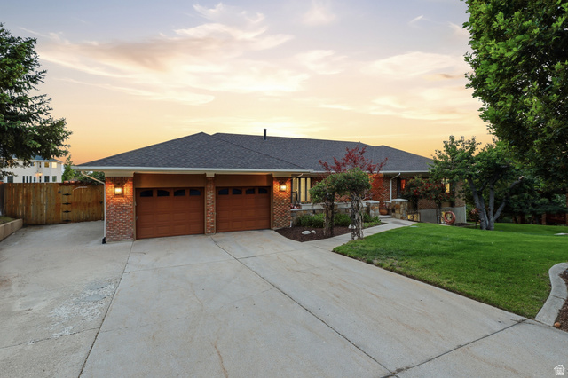 2342 Charros Road Sandy, UT 84092 - Photo 70 of 94 Brick facade ranch-style residence featuring a dual-bay garage with wood-finish doors, a concrete driveway, and mature landscaping
