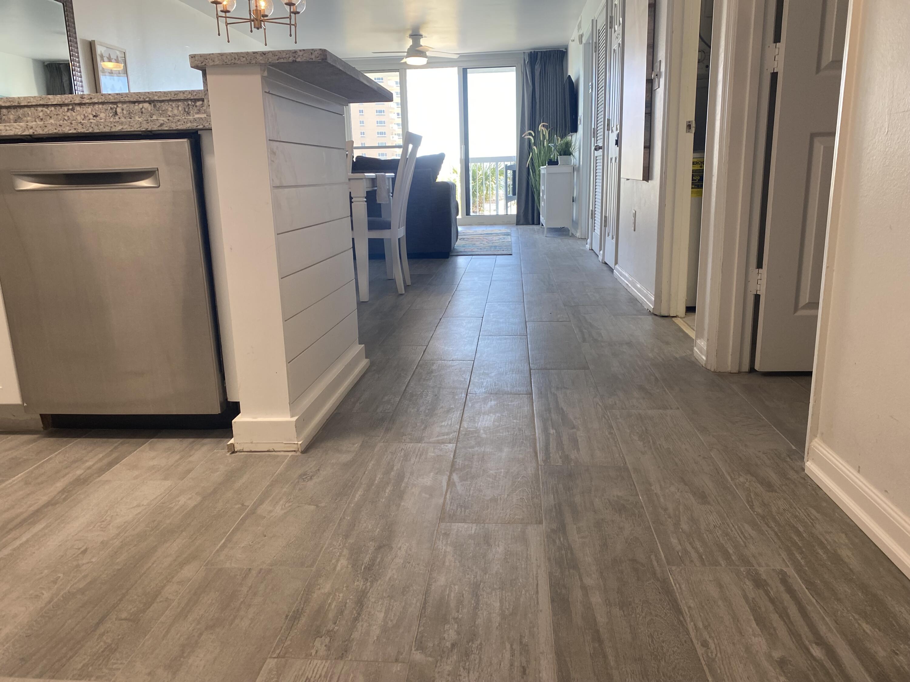 1002 Highway 98, Unit 316 Destin, FL 32541 - Photo 30 of 31 a view of a refrigerator in kitchen and an empty room with wooden floor windows
