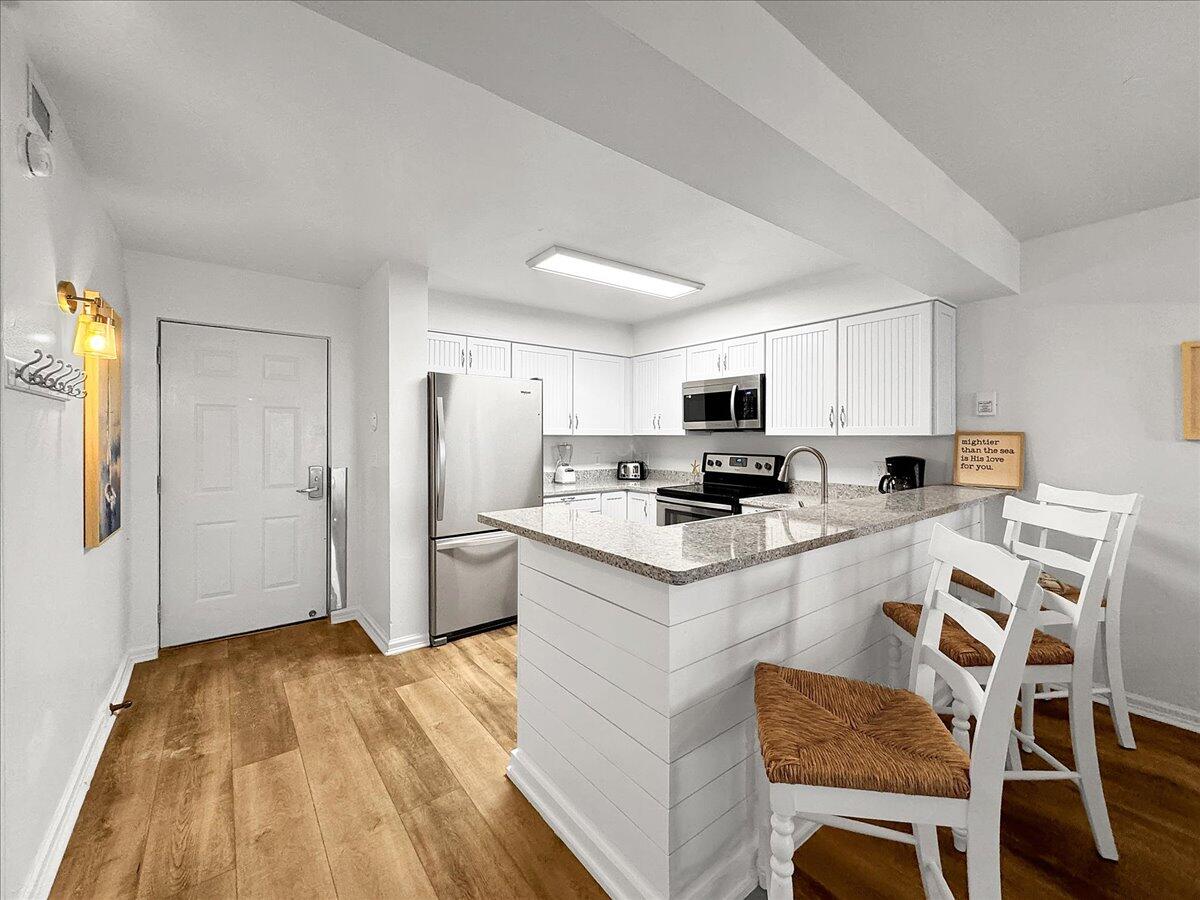 1002 Highway 98, Unit 316 Destin, FL 32541 - Photo 8 of 31 a kitchen with stainless steel appliances a stove top oven a sink a refrigerator white cabinets and wooden floor