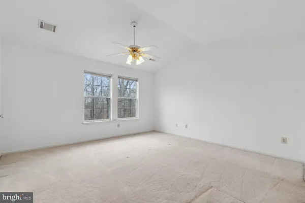 an empty room with windows and chandelier fan