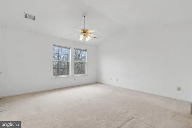 an empty room with windows and chandelier fan