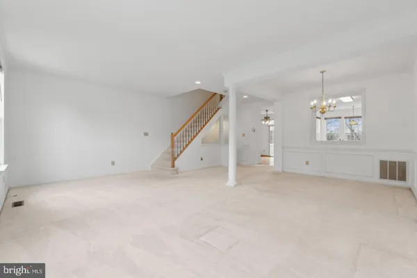 an empty room with chandelier fan and windows