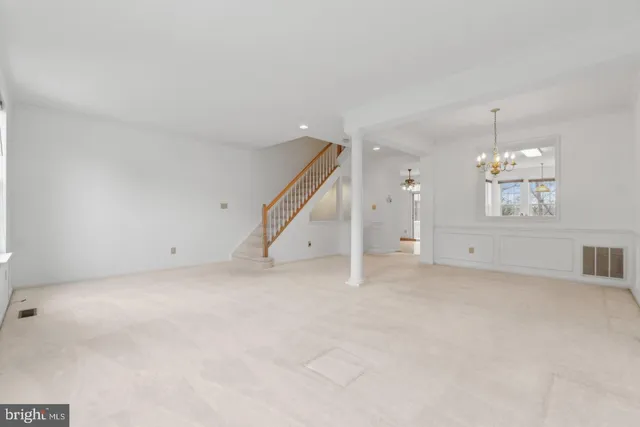 an empty room with chandelier fan and windows