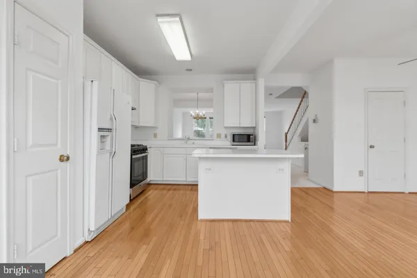 a kitchen with white cabinets and wooden floor