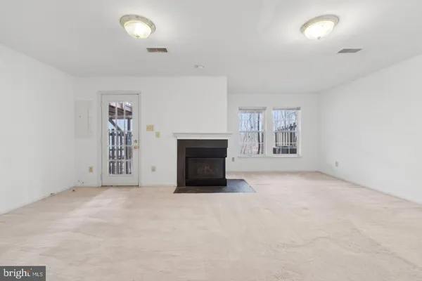 an empty room with windows and fireplace