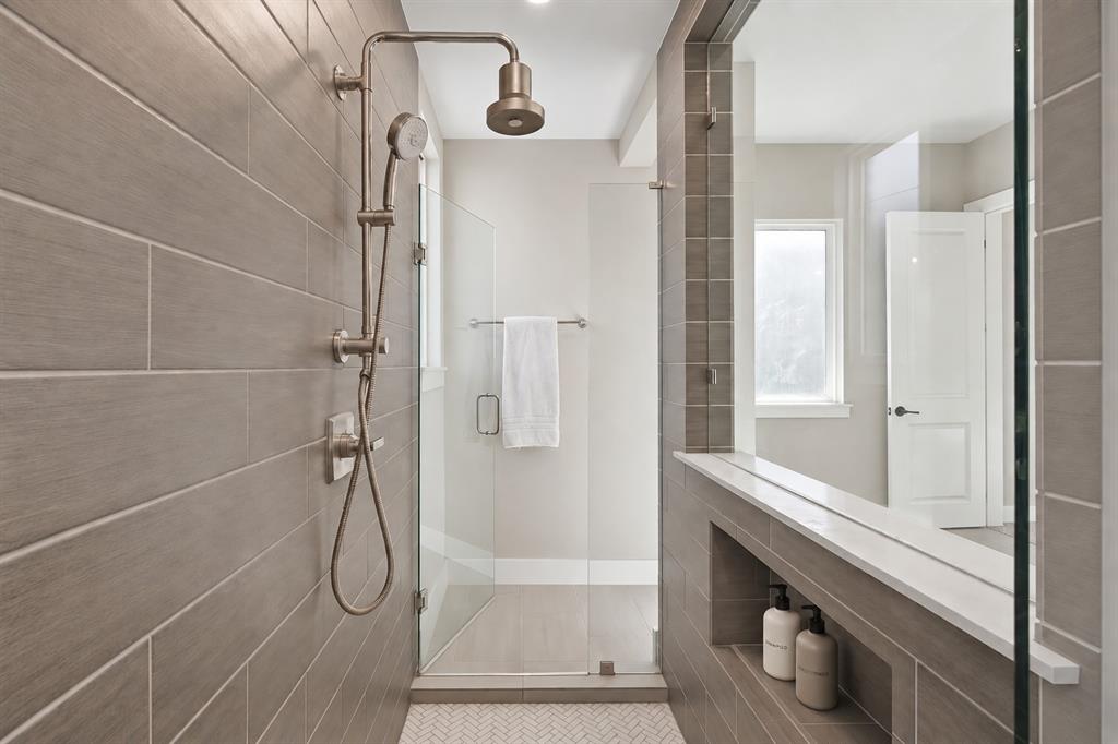 8408 Twistpine Road Frisco, TX 75035 - Photo 18 of 38 Walk-in shower with full glass enclosure, rainfall showerhead, and a built-in shelving niche with a stone surface