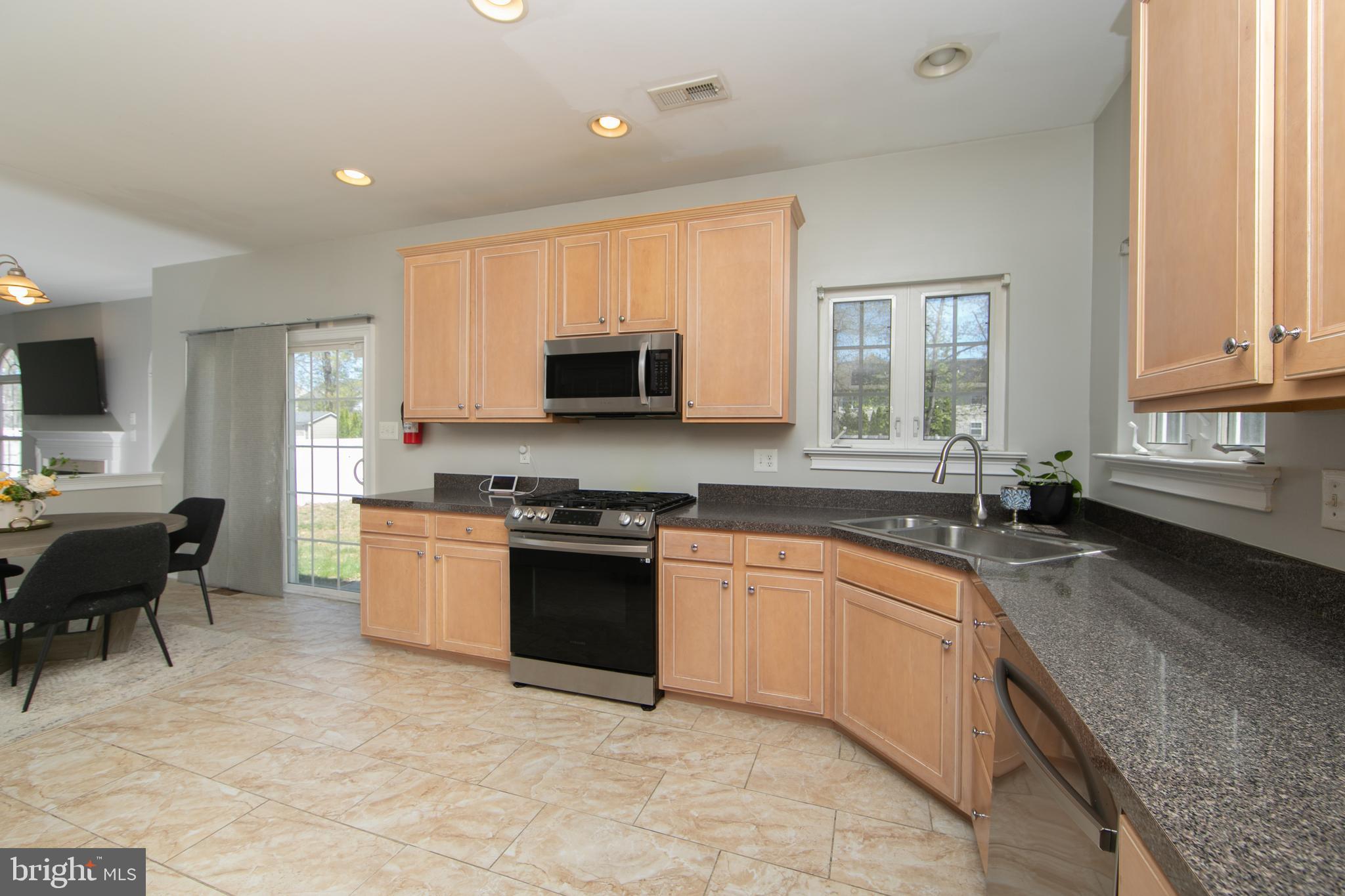 4 Conifer Way Sicklerville, NJ 08081 - Photo 17 of 39 a large kitchen with stainless steel appliances granite countertop a stove top oven a sink dishwasher a dining table and chairs with wooden floor