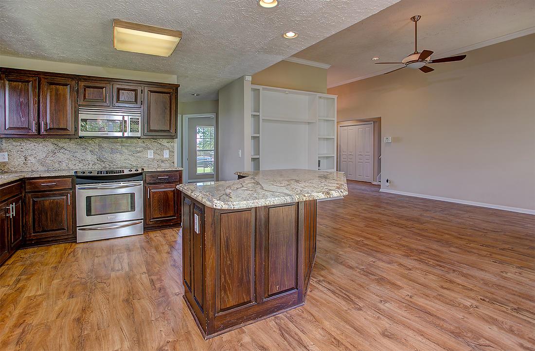 1228 Hunters Point Lane Spring Hill, TN 37174 - Photo 3 of 23 a kitchen with kitchen island granite countertop wooden floors and stainless steel appliances