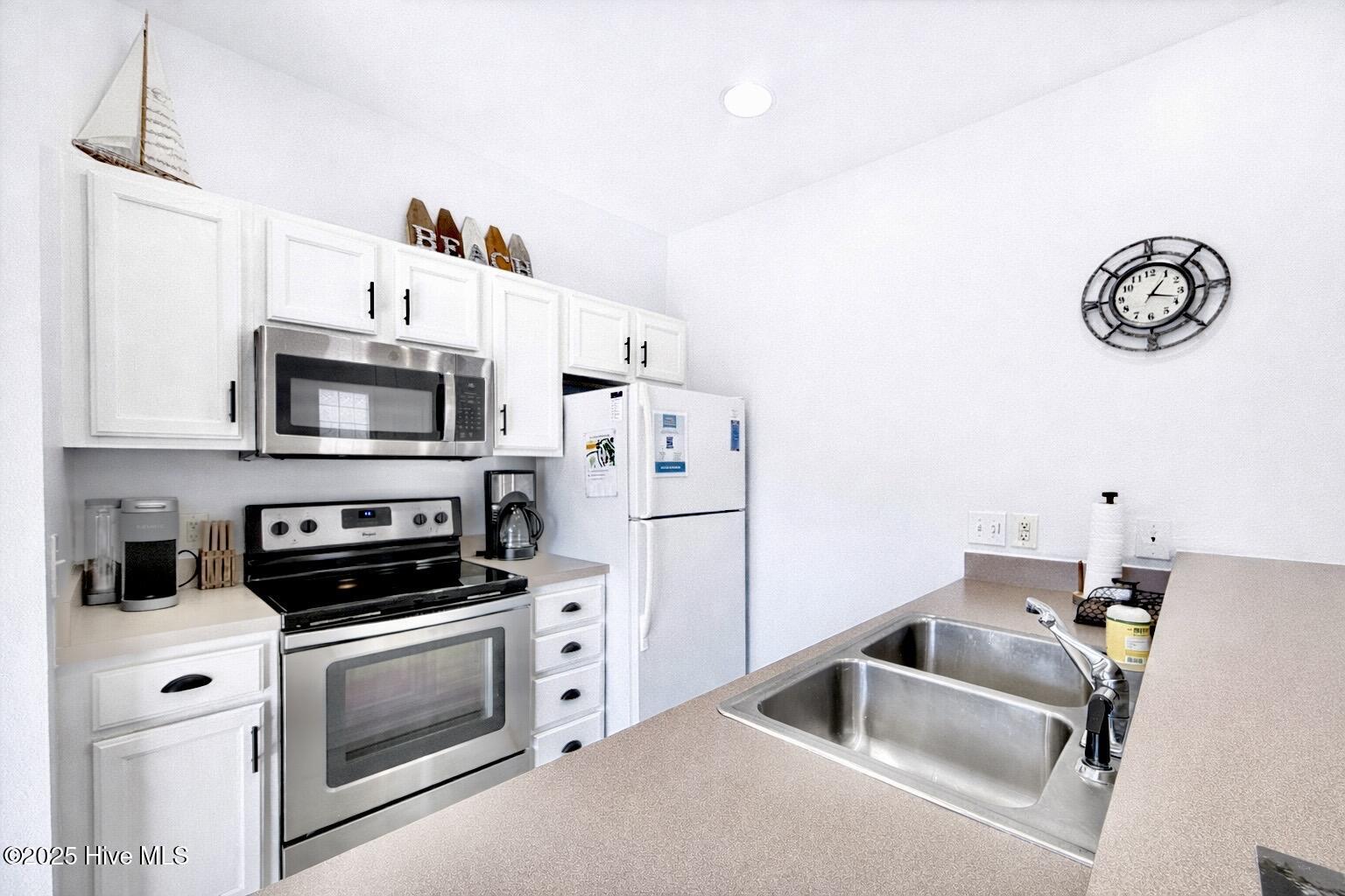165 Royal Poste Road, Unit 2911 Sunset Beach, NC 28468 - Photo 6 of 24 Updated kitchen with white cabinetry, stainless steel appliances, breakfast bar, and open sightlines to living area.